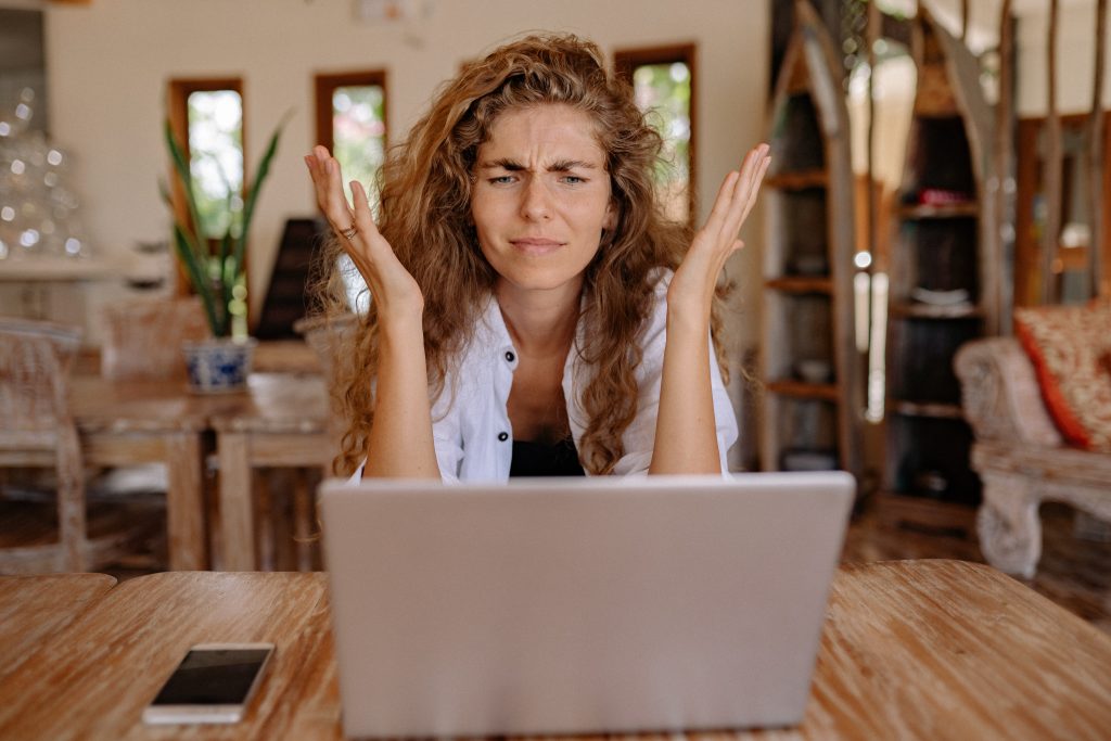 mujer frente a computadora con gesto de confusión