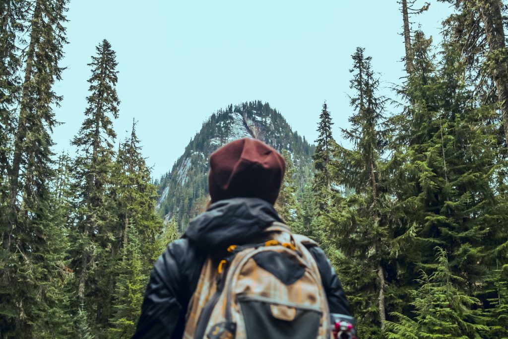 mujer en el bosque viendo hacia una montaña y con actitud positiva ante la vida