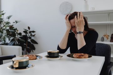 mujer sentada en el comedor con las manos sobre el rostro