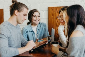 cuatro personas jóvenes practicando la comunicación asertiva en el trabajo