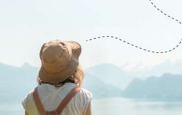 mujer de espaldas viendo hacia paisaje de montañas y lago