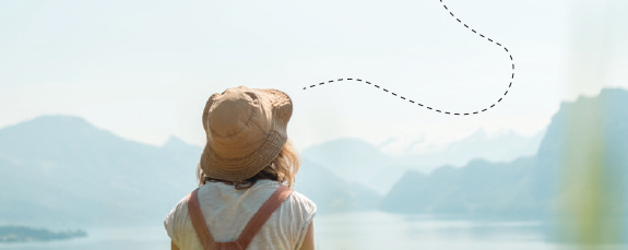 mujer de espaldas viendo hacia paisaje de montañas y lago