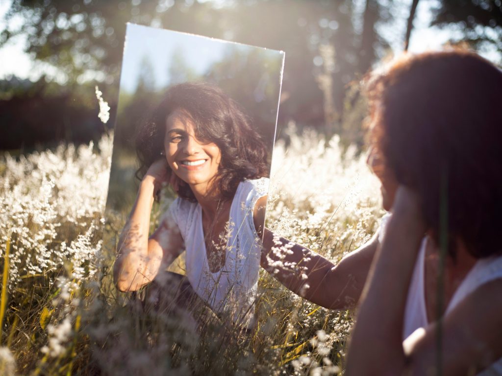 mujer con camisa floral-azul y blanca sonriendo mostrando manejo de emociones