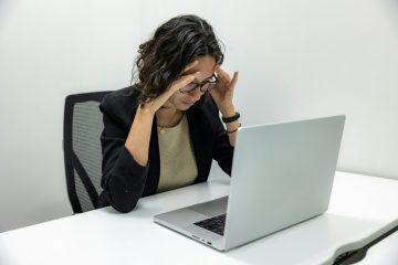 mujer sintiendo frustración laboral sentada frente a una computadora portátil