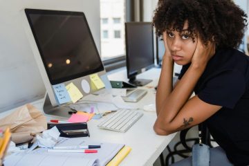 mujer sentada frente a escritorio sin buena salud mental en el traajo